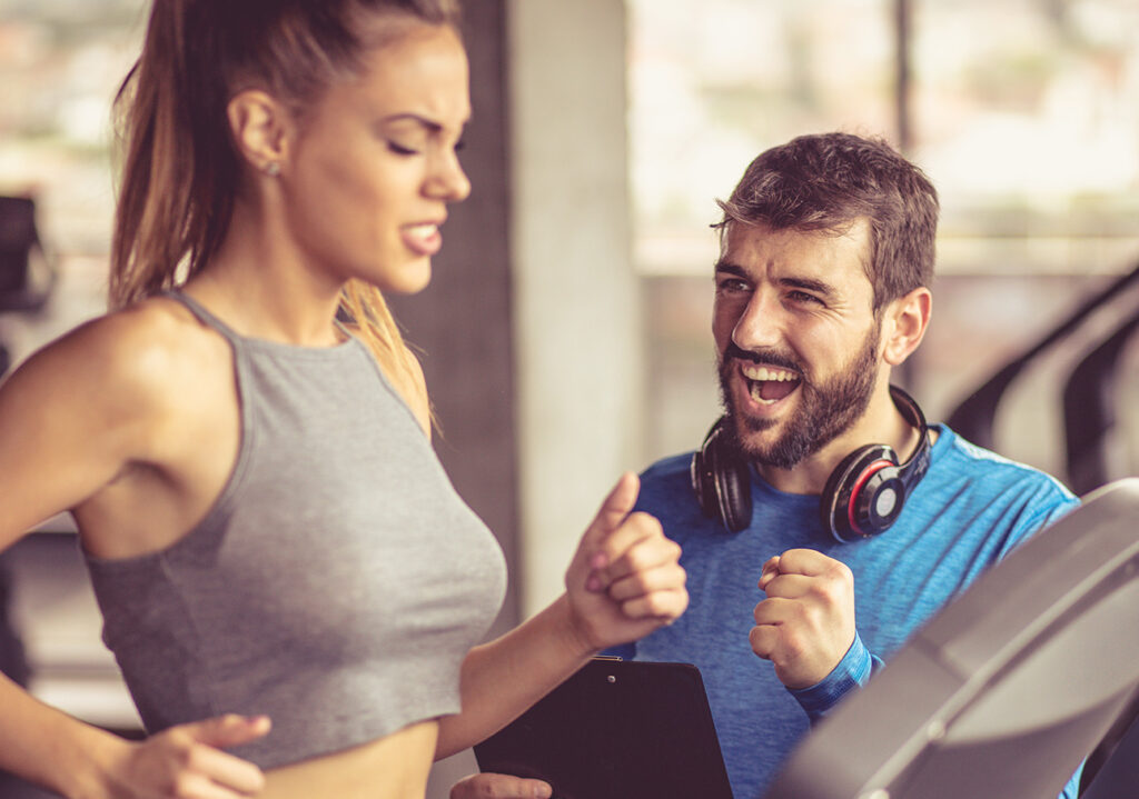 Personal Trainer unterstützt eine junge Sportlerin beim Lauftraining